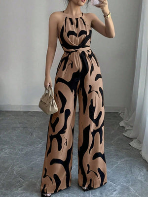 Elegant wide-leg jumpsuit in tan with abstract black print, halter neck, and draped bodice.