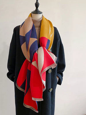 Geometric patterned soft scarf with fringes in red, blue, yellow, tan, and cream colors.