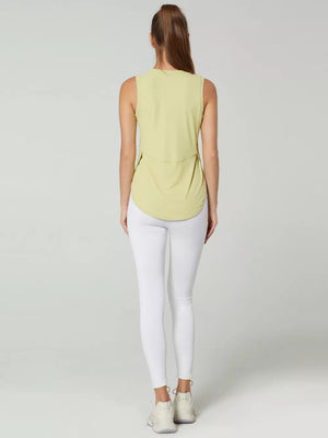 Sleeveless light yellow tank top with curved hem and side slits, worn with white leggings.
