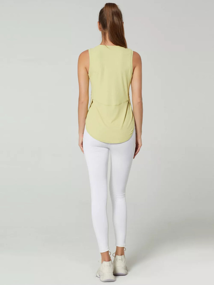 Sleeveless light yellow tank top with curved hem and side slits, worn with white leggings.