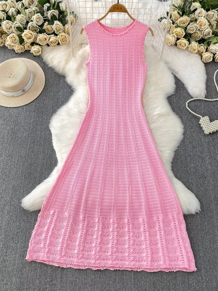 Pink knit midi dress with pearl neckline and cutout details.