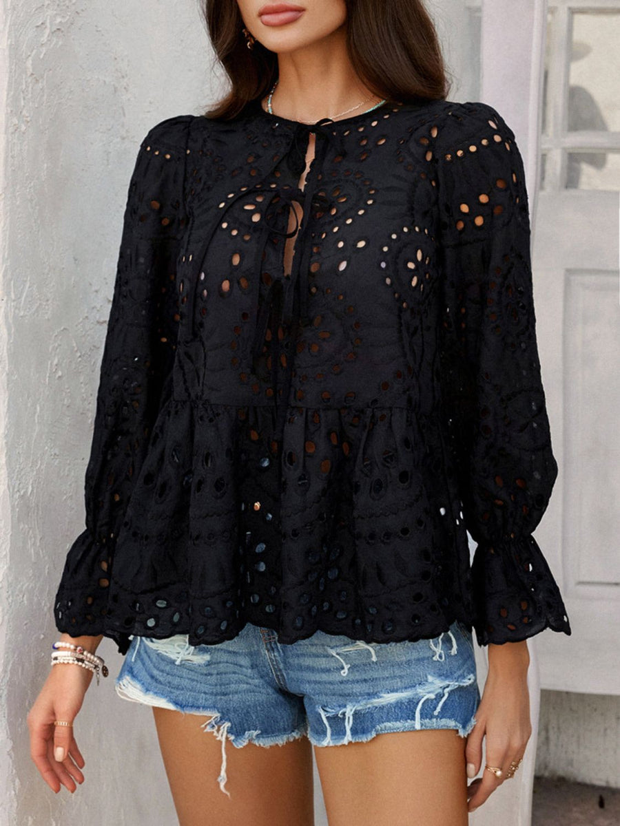 Black eyelet embroidered peplum blouse with tie neck and ruffled cuffs.
