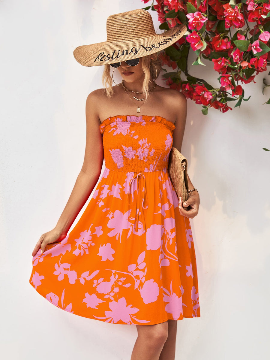 Orange smocked bandeau floral mini dress with drawstring waist and ruffled hem.