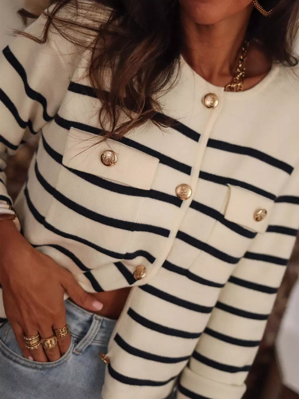 Navy and cream striped button-front cardigan with gold buttons and chest pockets.