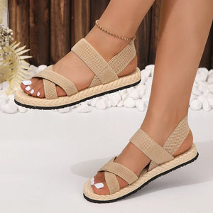Beige woven sole crossover sandals with elastic straps and espadrille trim.