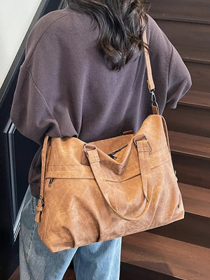 Brown faux leather tote bag with top handles and adjustable strap, worn with a brown waffle knit top.