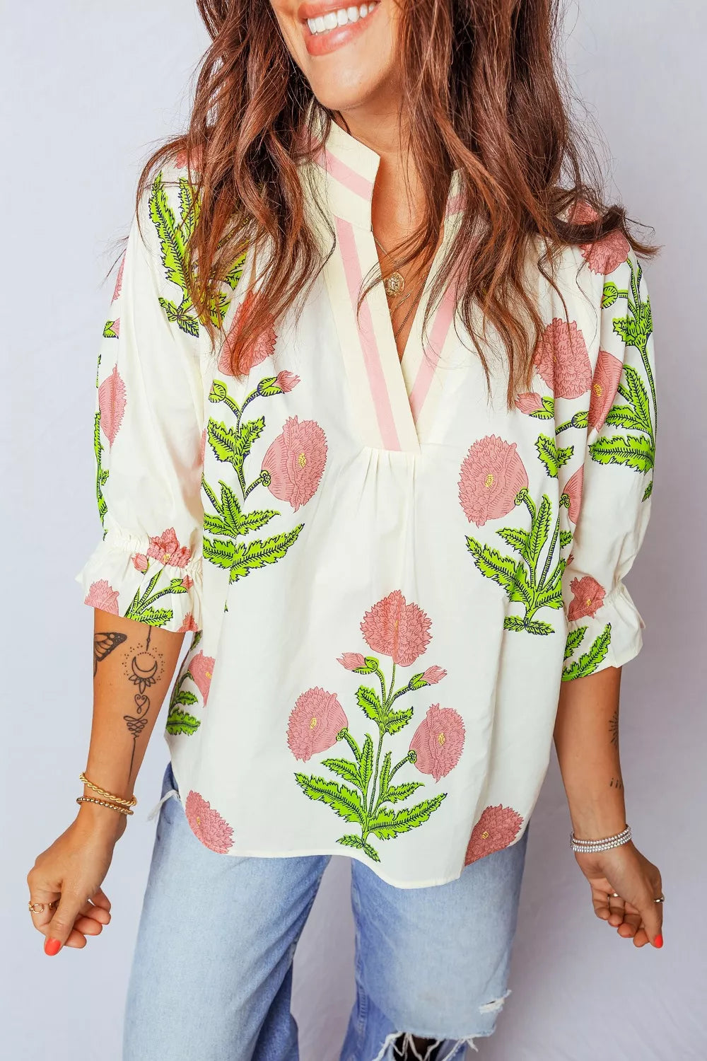 Vibrant floral cotton blouse with ruffled sleeves and notched neckline.
