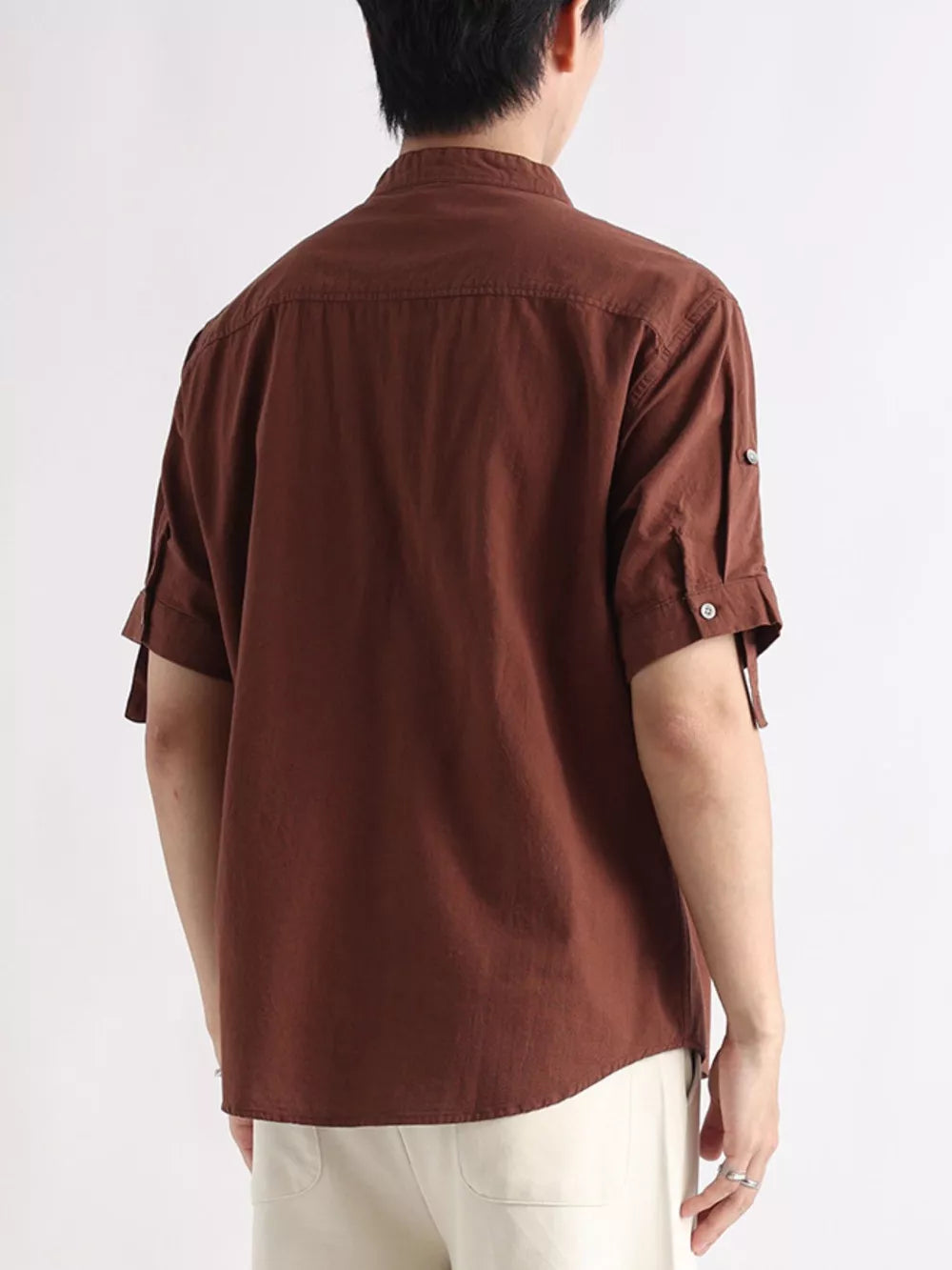 Brown cotton button-down shirt with rolled-up sleeves and button detail.