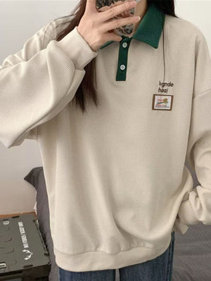 Textured waffle-knit polo sweatshirt in cream with green collar and button placket.