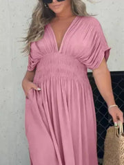 Pink V-neck maxi dress with dolman sleeves, smocked waist, and pockets.