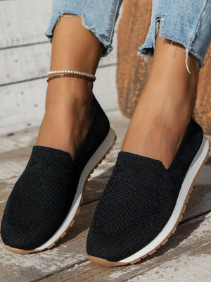 Black breathable knit slip-on sneakers with white soles and tan outsoles.
