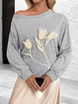 Gray boat neck sweater with delicate floral applique detail.