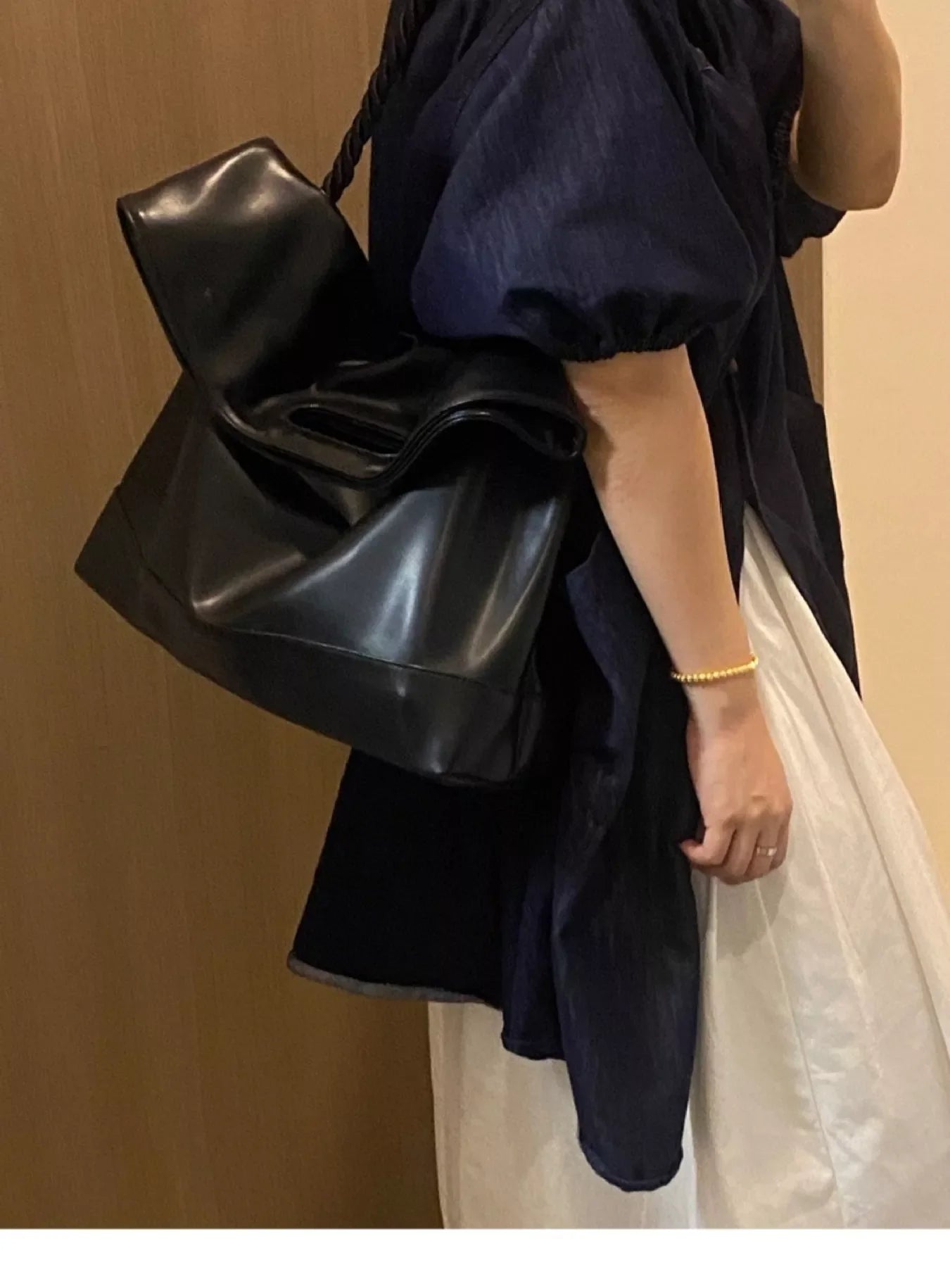 Black oversized PU leather tote bag with a slouchy, crumpled design and braided strap.