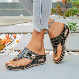 Black crocodile-embossed wedge thong sandals with gold buckle detail.