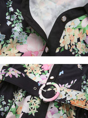 Maternity dress with floral print, black trim, buttons, and a patterned belt with a round buckle.