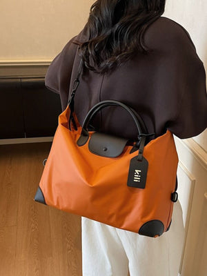 Orange travel duffel bag with black trim and a detachable luggage tag.