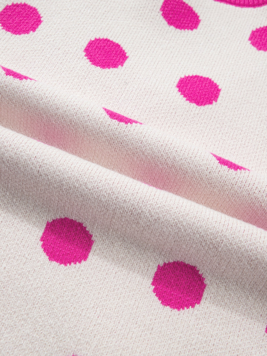 Knit top with cream base and hot pink polka dots, featuring puff sleeves.