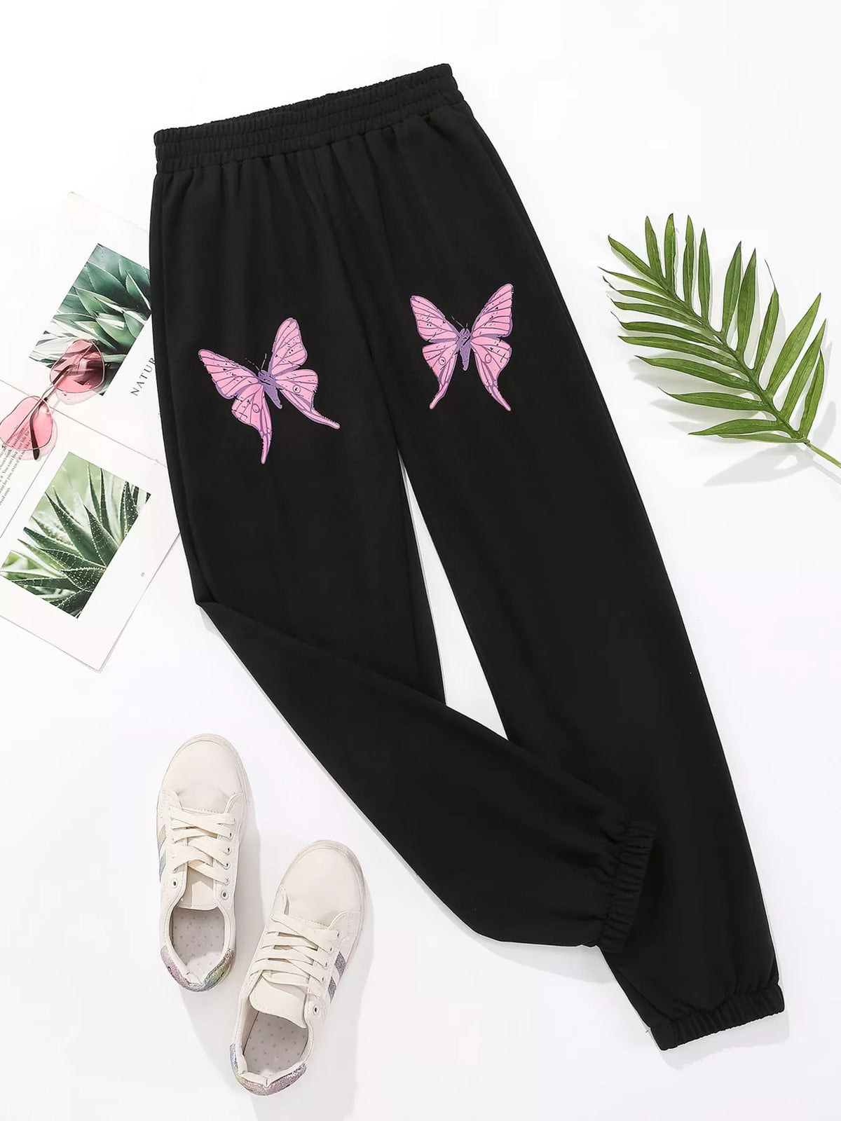 Black sweatpants with pink butterfly embellishments and cuffed ankles