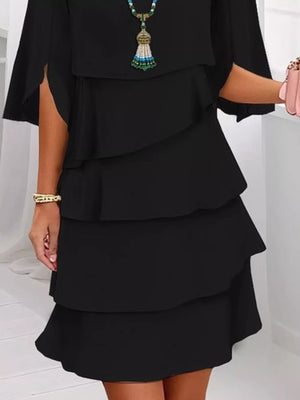 Black ruffled layered dress with flutter sleeves and slit detail.