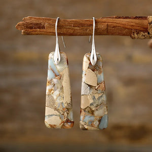 Textured stone drop earrings with silver hooks, featuring natural stone patterns in tan and blue.