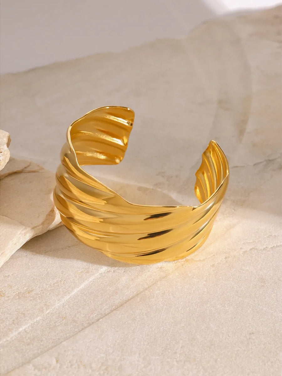 Gold cuff bracelet with sculpted wave texture, 18K gold-plated and adjustable.