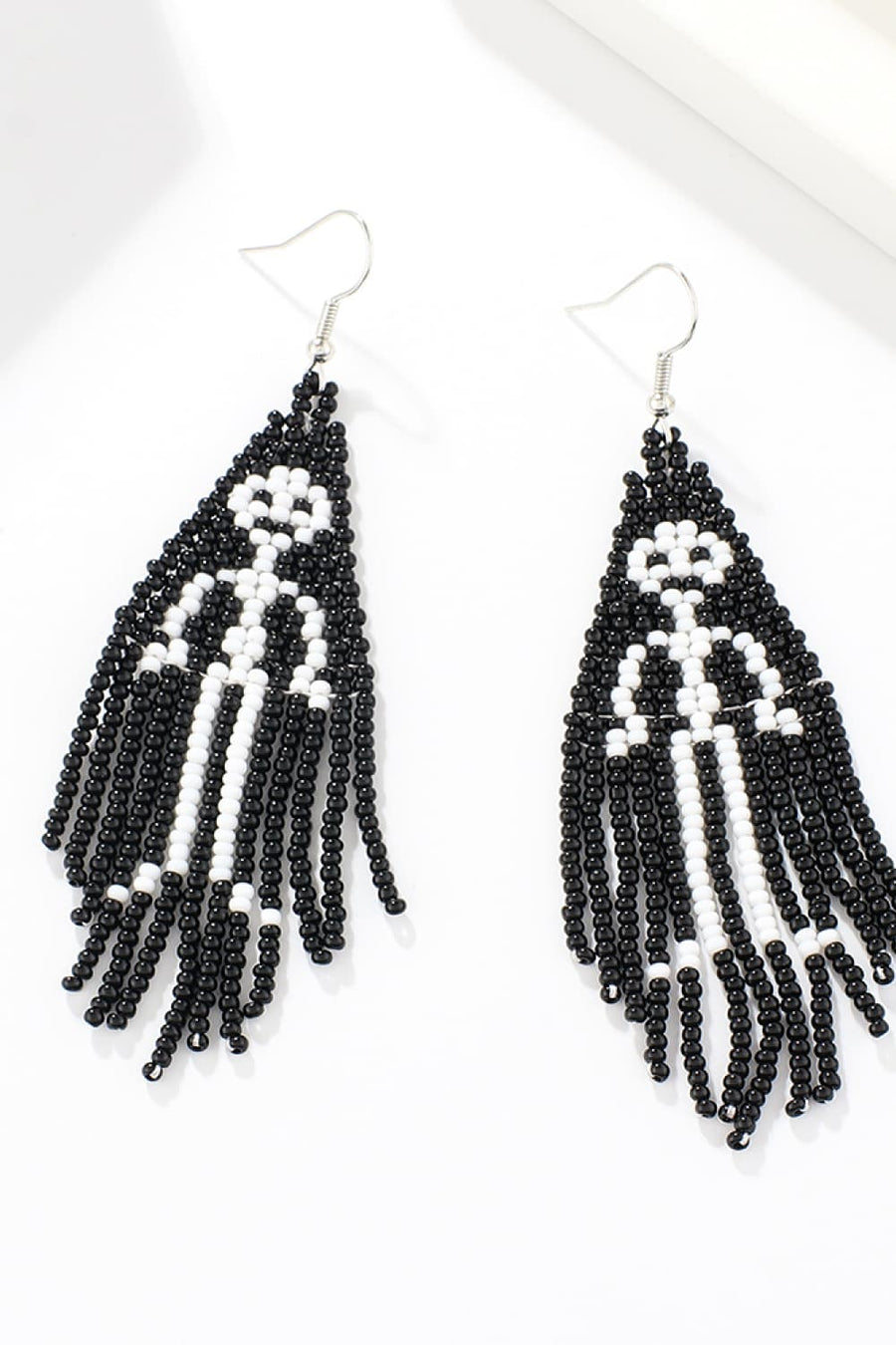 Beaded ghost fringe earrings in black and white with dangling strands.