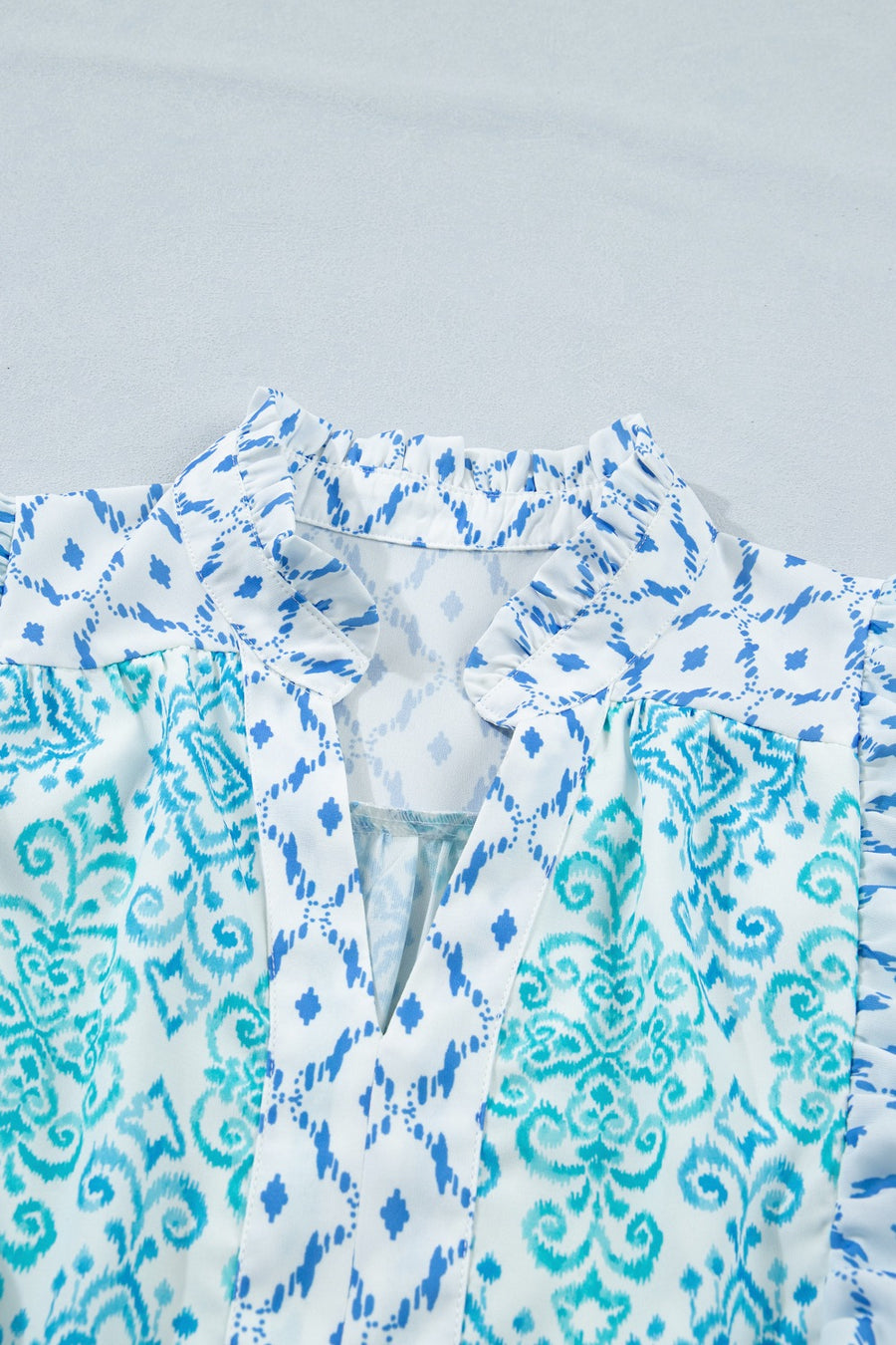 Patchwork mini dress with blue ikat and damask prints, V-neck, and ruffled collar.