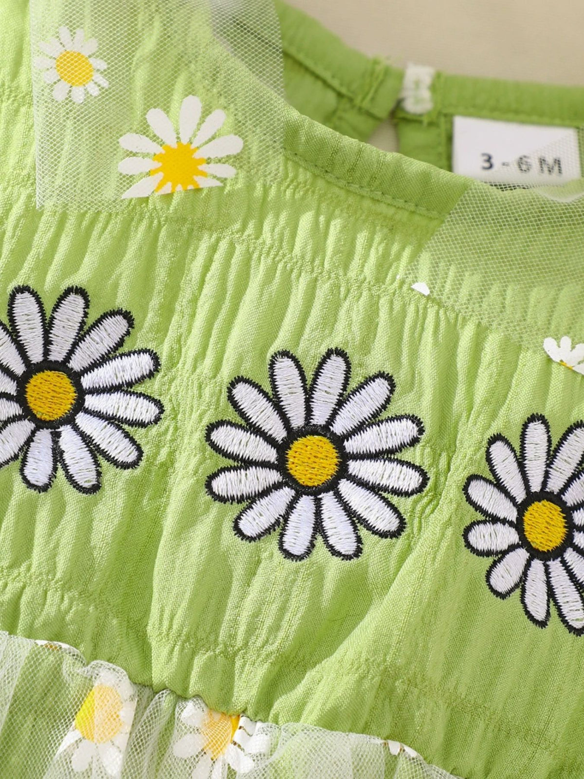 Green baby dress with daisy embroidery and mesh trim.