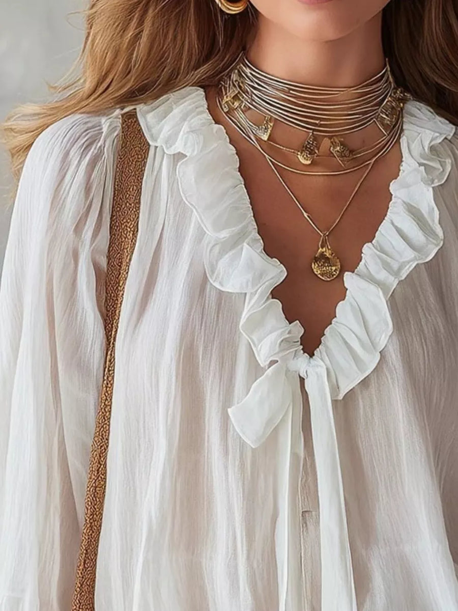 White frilled tie-front shirt with ruffled neckline and gold trim detail.