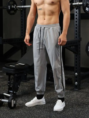Gray track pants with black zip detail and drawstring waist.