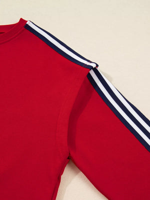 Red sweatshirt with navy and white varsity stripe detail on the sleeves.