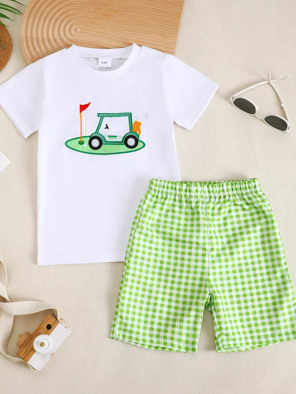 White baby t-shirt with golf cart graphic and green gingham shorts