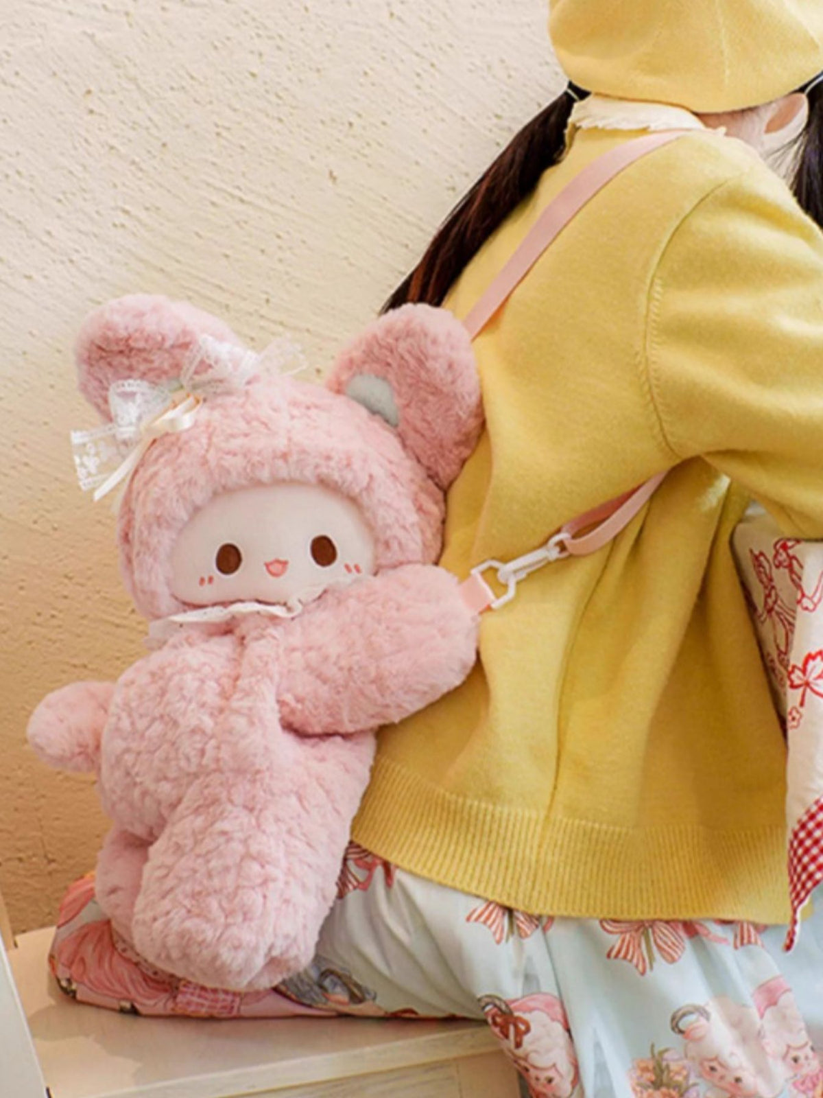 Pink plush bunny backpack with lace bow detail and white collar.