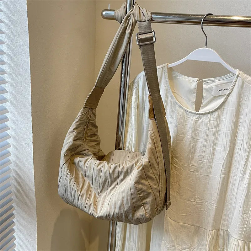 Beige quilted crescent shoulder bag with adjustable strap and leather accents.