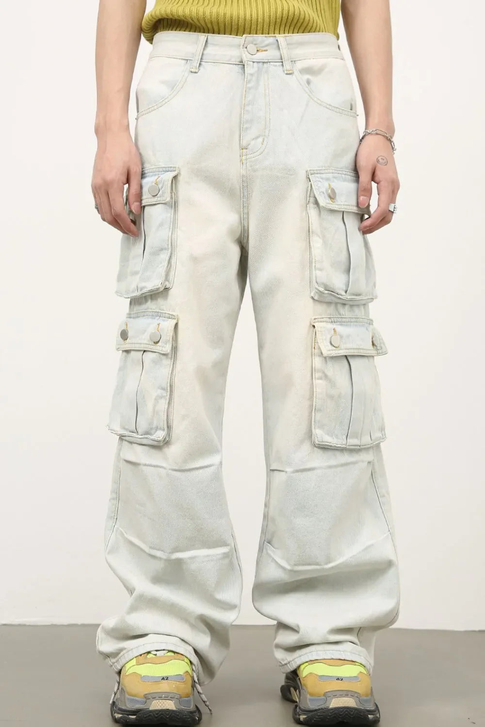 Light wash denim cargo pants with multiple pleated pockets and wide legs.