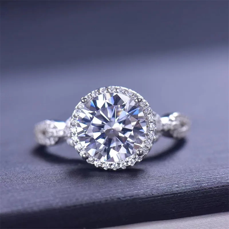 Silver halo moissanite engagement ring with twisted band and round brilliant center stone.