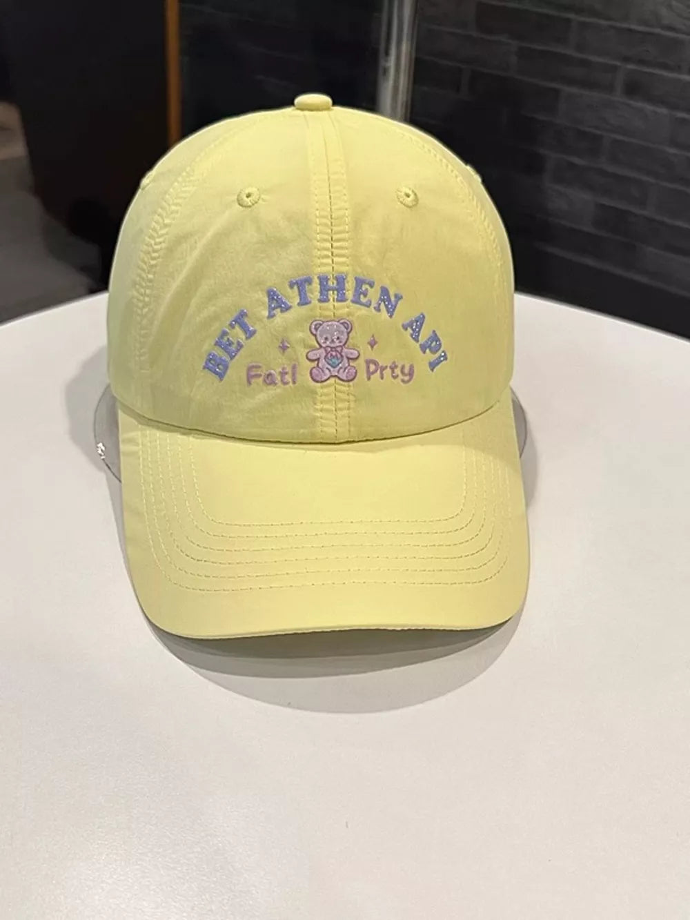 Yellow baseball cap with embroidered teddy bear and text detail