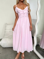 Pink midi dress with spaghetti straps, ruffled neckline, smocked waist, and tie detail.