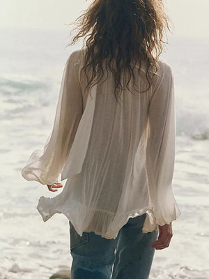 White sheer ruffle trim beach cover-up with long flowy sleeves and a ruffled hem.