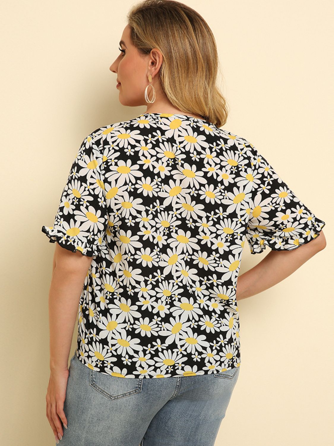 Daisy print blouse with ruffle sleeves and knot detail, floral pattern on black.