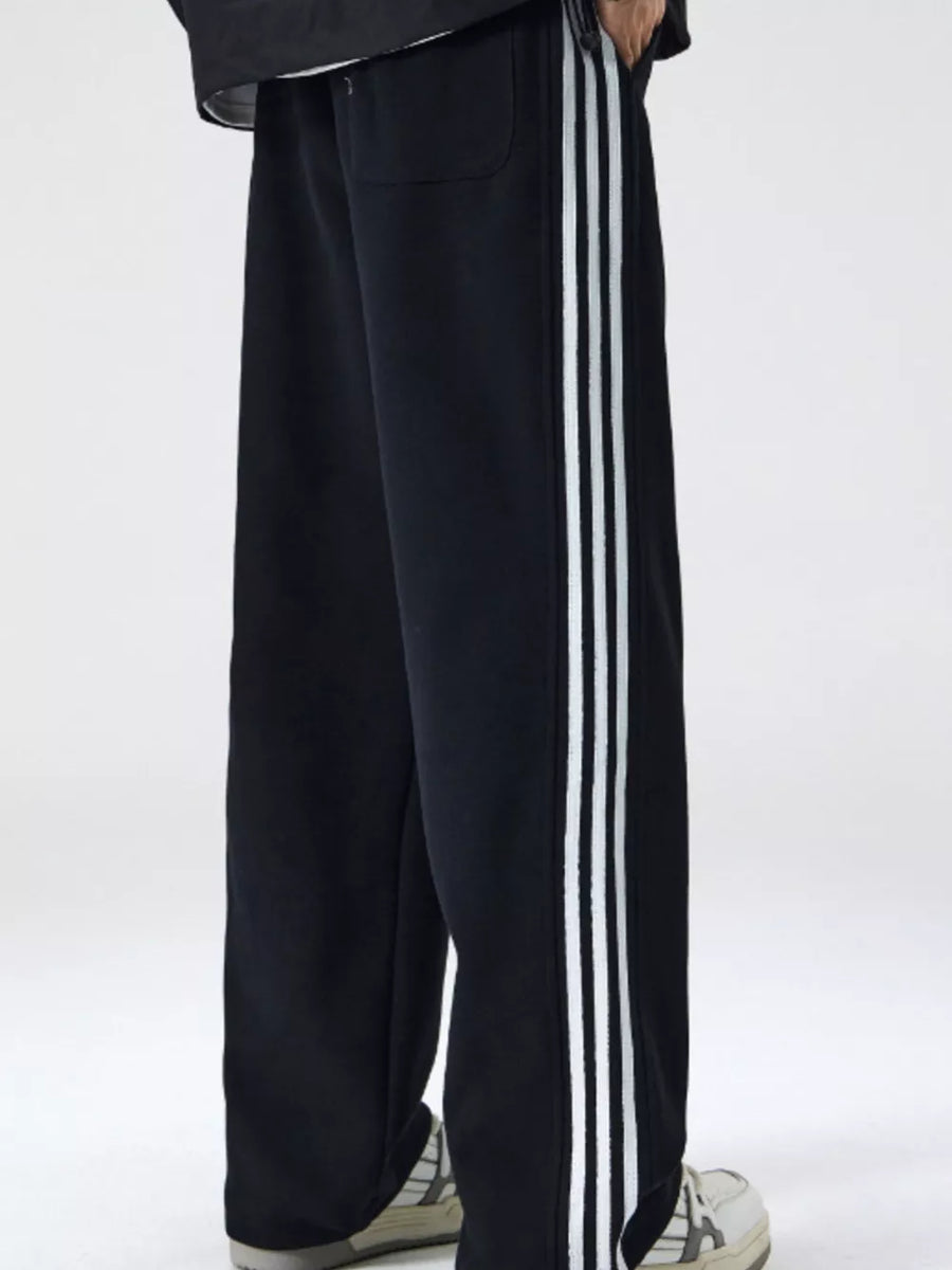 Black men's sweatpants with white side stripes and a relaxed fit.