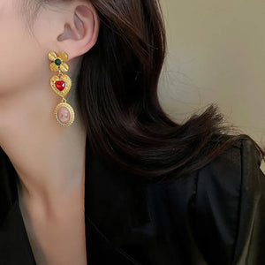 Gold cameo drop earrings with heart and flower details.