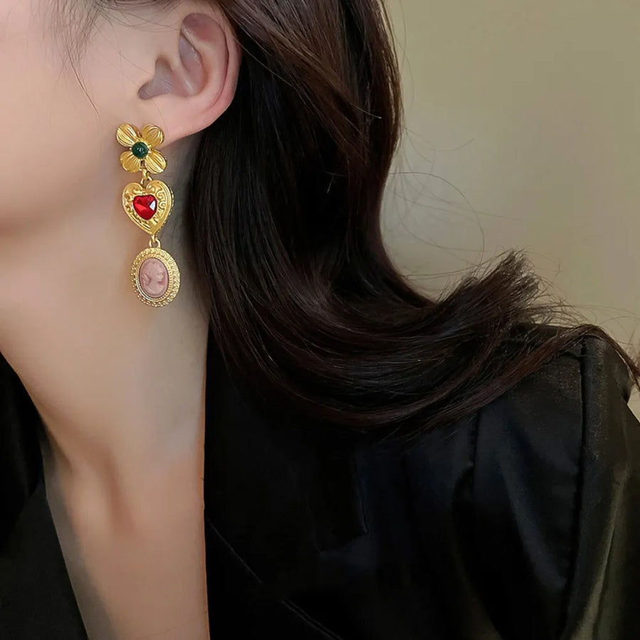 Gold cameo drop earrings with heart and flower details.