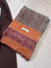 Textured wool color block scarf with orange, burgundy, and brown stripes.