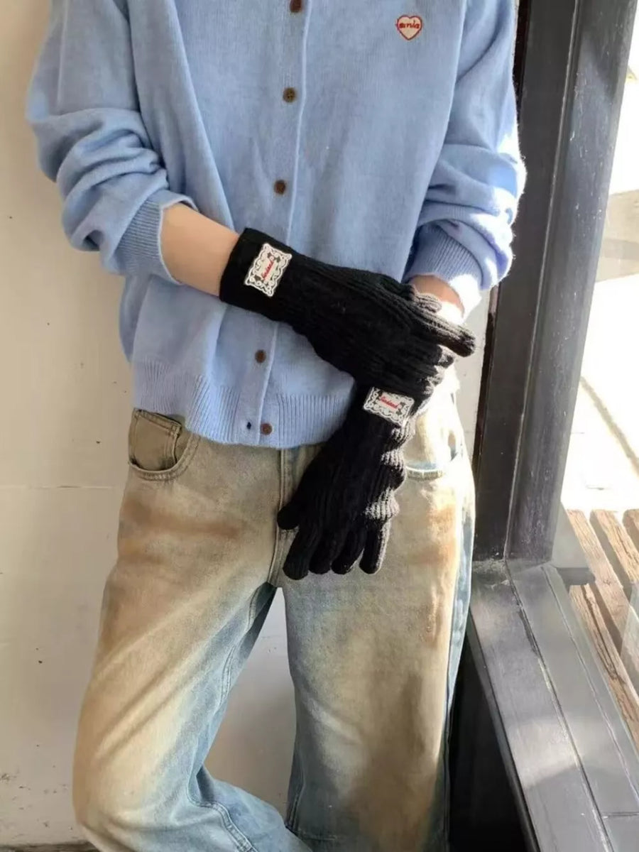 Black cable knit gloves with decorative patch detail.