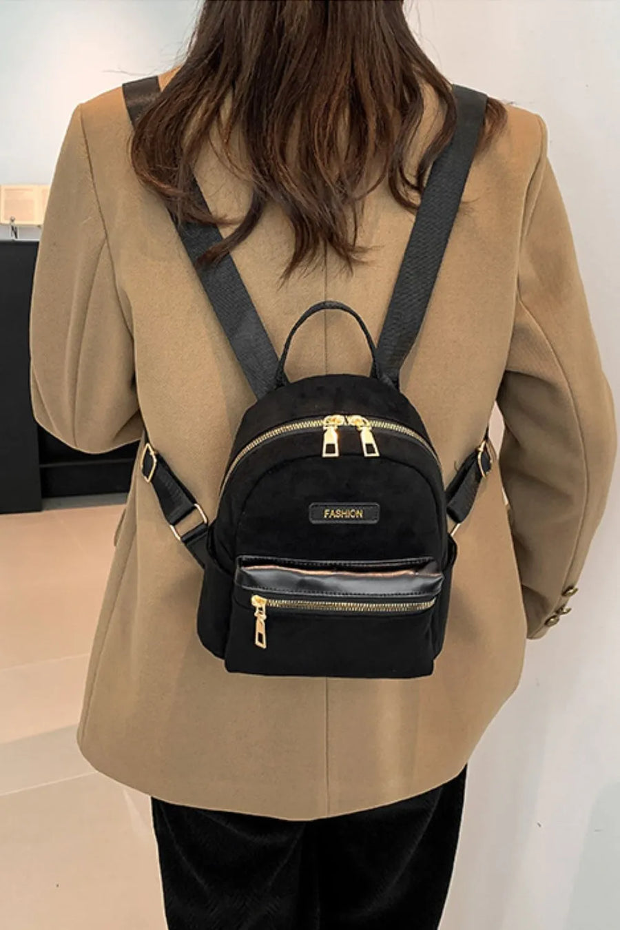 Black suede mini backpack with golden zips and "FASHION" detail