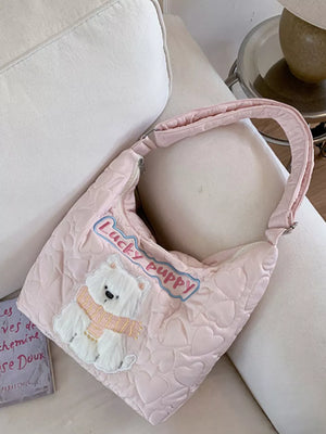Blush pink quilted crossbody bag with a white bear applique and "Lucky puppy" text.