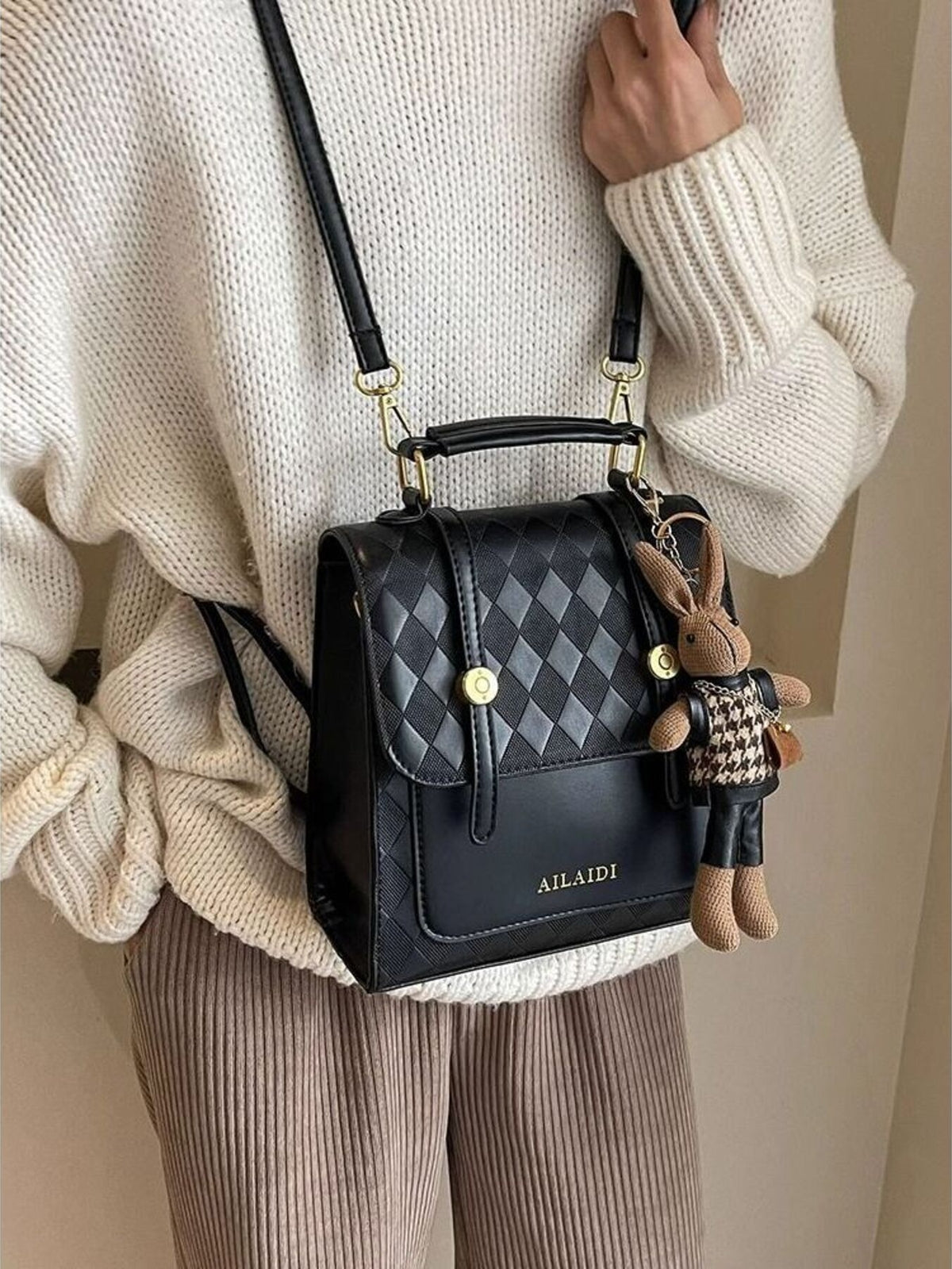 Black quilted flap backpack bag with diamond pattern and bunny charm