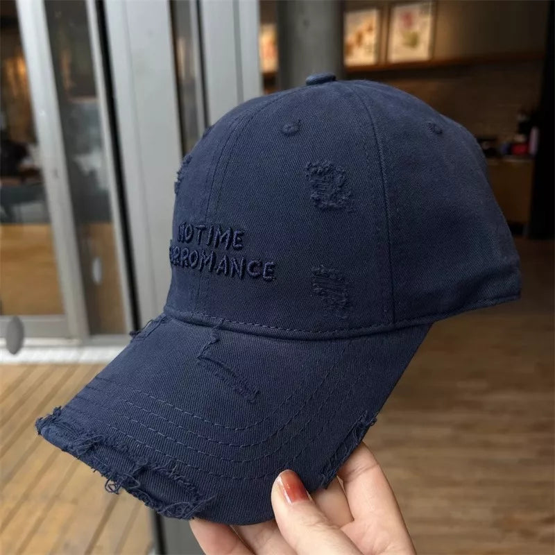 Navy blue cotton baseball cap with distressed details and embroidered text.