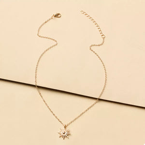 Gold sunburst pendant necklace with delicate chain and lace trim detail.